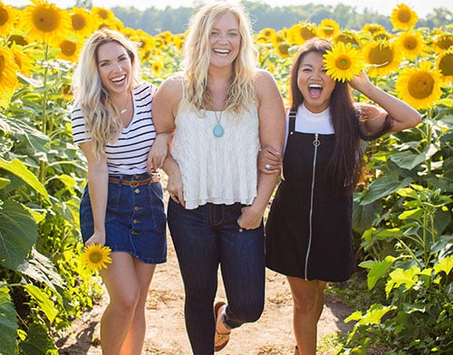 Three happy women in a sunflower field